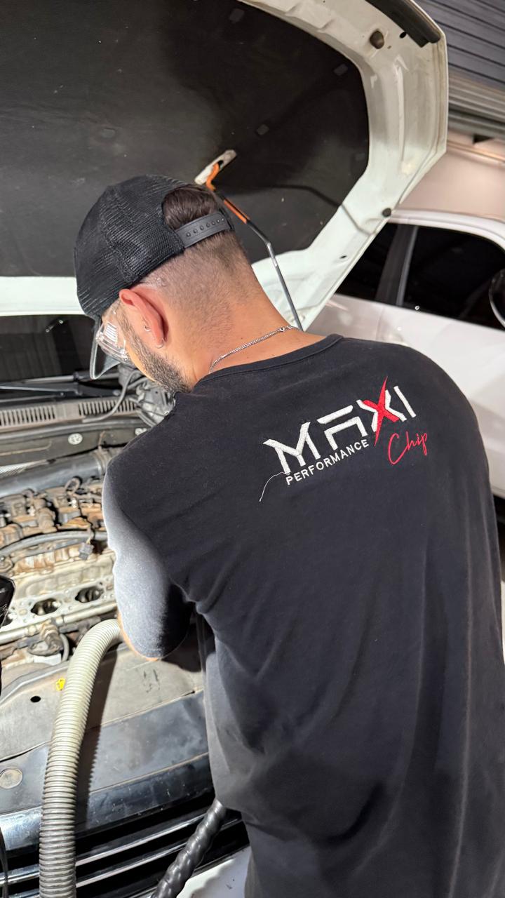 Mecânico fardado da Maxi Chip trabalhando sobre motor aberto