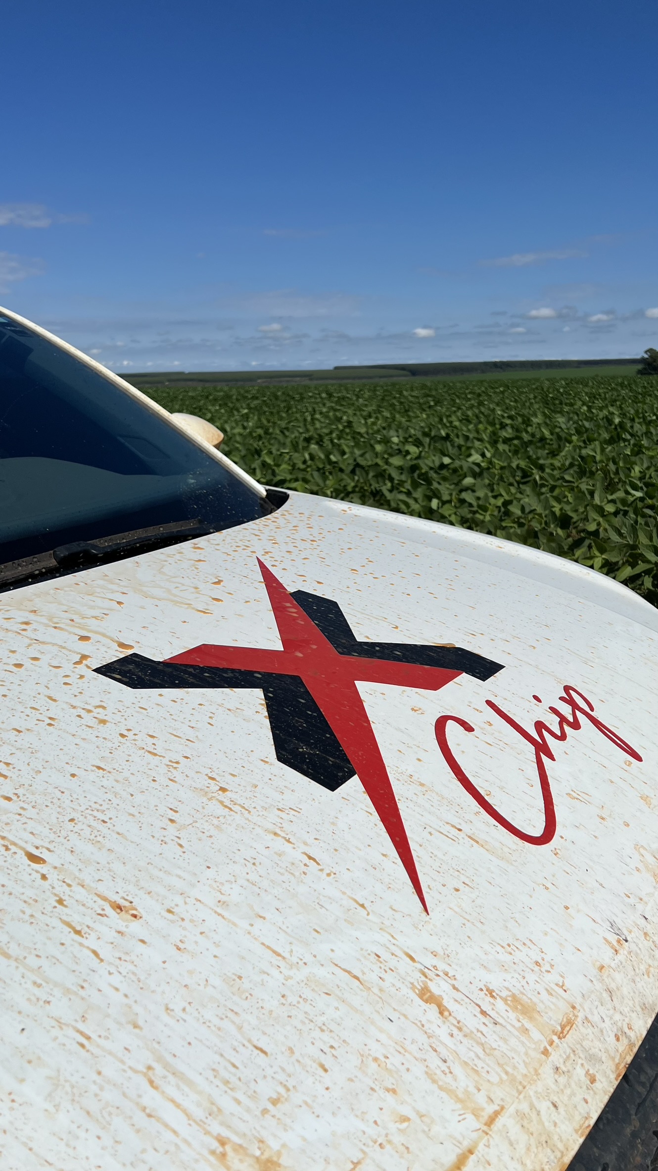 Capô do carro Maxi com a marca sobre a lavoura de soja