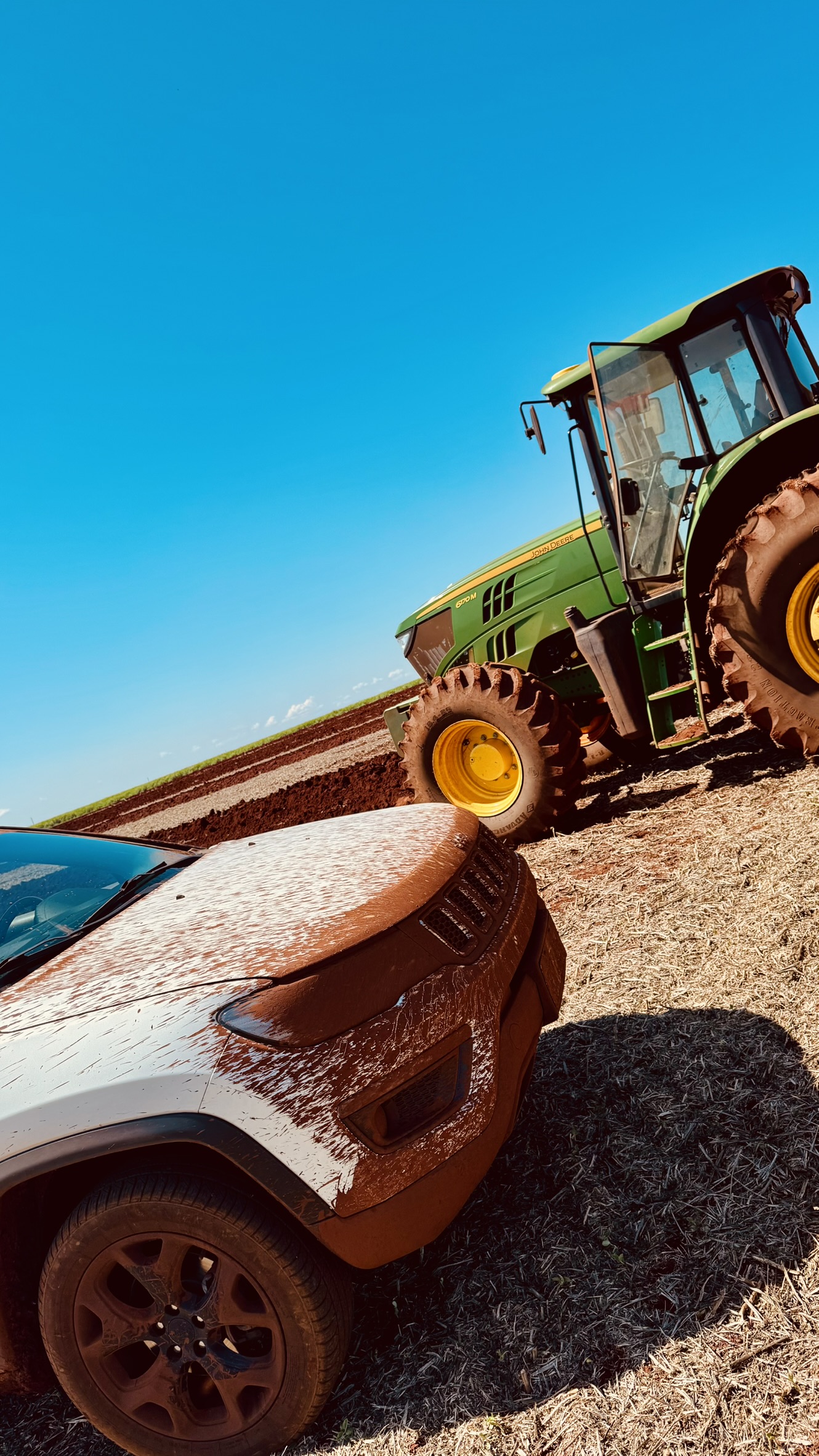 SUV da Maxi enlameado ao lado de trator John Deere na lavoura