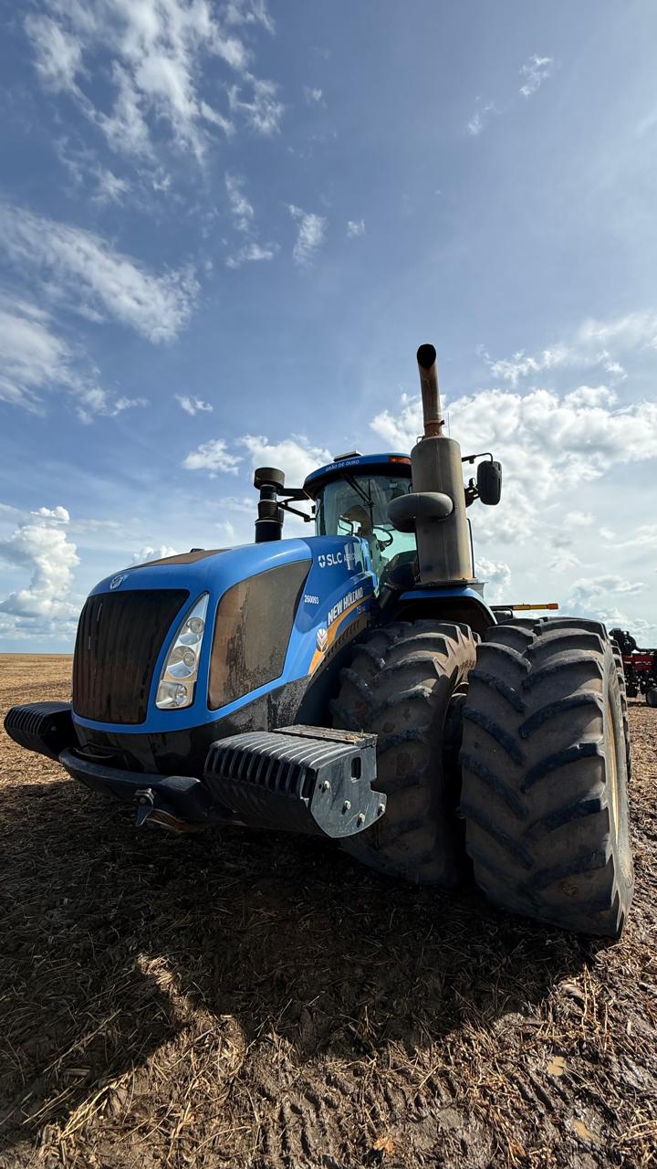 Trator New Holland azul de frente no campo